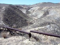 Half-buried and rusted pipelines crisscross these hills
