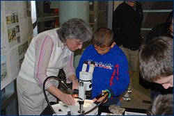 Museum scientist Diane Erwin shows a young visitor thin sections of petrified wood