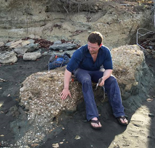 Larry Taylor in the field in Panama, getting ready to chisel a fossil whale barnacle out of the rocky outcrop he’s sitting on. 