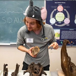 Nick Spano wearing an elephant hat and doing paleontology outreach