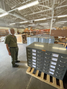 Prof. Doyle standing next to flat files filled with fossils.