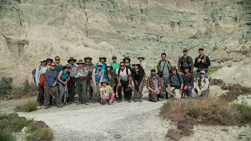 A group of students and National Park Ranger in front of a beige and celadon colored outcrop